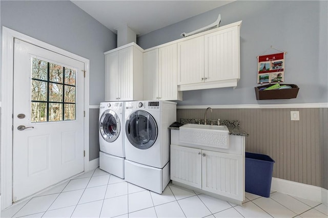 laundry room featuring light tile patterned floors, a sink, separate washer and dryer, cabinet space, and wainscoting