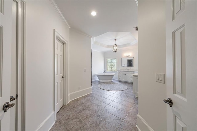 corridor featuring a raised ceiling, baseboards, ornamental molding, visible vents, and recessed lighting