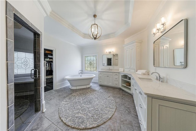 bathroom with a notable chandelier, a sink, a freestanding tub, ornamental molding, and two vanities
