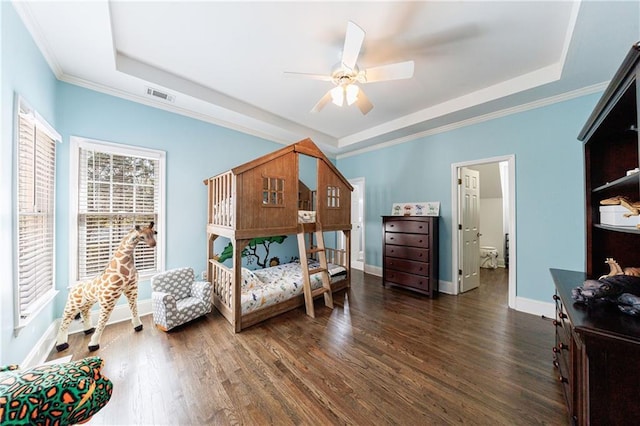 bedroom with a tray ceiling, visible vents, baseboards, and dark wood-style floors