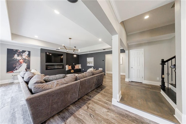 living area with recessed lighting, wood finished floors, baseboards, stairway, and a raised ceiling