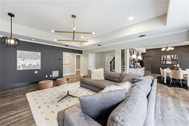 living area featuring an inviting chandelier, wood finished floors, a tray ceiling, and baseboards