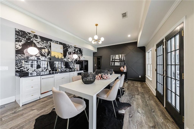 dining room featuring visible vents, an accent wall, a chandelier, and dark wood-style floors