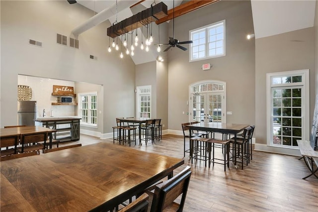 dining area featuring a high ceiling, visible vents, ceiling fan, and wood finished floors