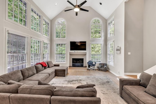 1253 Rivermark Ct, Lawrenceville, GA 30043 - living room with high vaulted ceiling, healthy amount of natural light, a ceiling fan, wood finished floors, and a fireplace with raised hearth