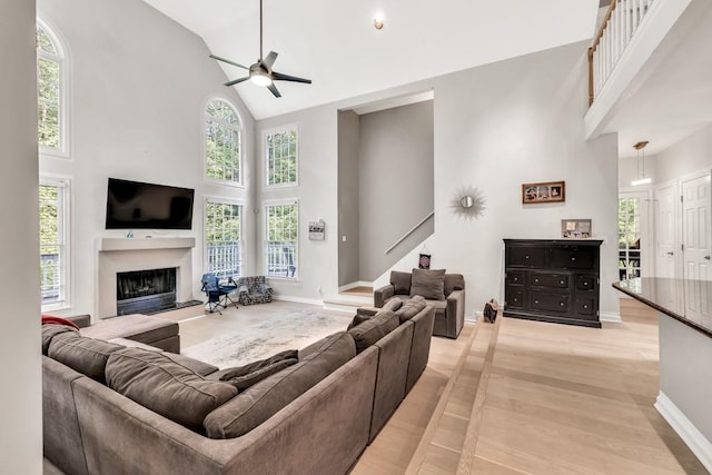 1253 Rivermark Ct, Lawrenceville, GA 30043 - living area with high vaulted ceiling, a fireplace with raised hearth, a ceiling fan, baseboards, and light wood-type flooring