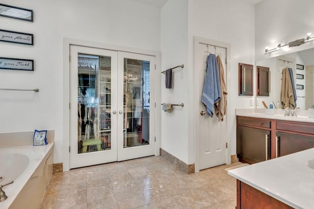 1253 Rivermark Ct, Lawrenceville, GA 30043 - bathroom featuring french doors, vanity, a garden tub, and baseboards