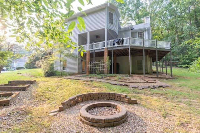 1253 Rivermark Ct, Lawrenceville, GA 30043 - back of property featuring a fire pit, a wooden deck, a ceiling fan, a chimney, and a vegetable garden