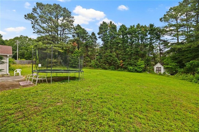 1230 Brook Meadow Ct, Lawrenceville, GA 30045 - view of grassy yard featuring a trampoline, a storage unit, an outbuilding, and a patio
