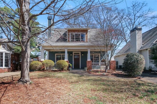 view of front of house featuring a porch, a chimney, and a front lawn