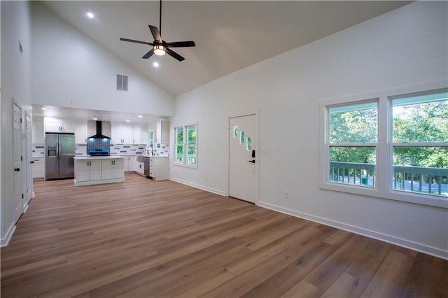 1342 Carter Rd, Decatur, GA 30030 - unfurnished living room with a ceiling fan, high vaulted ceiling, healthy amount of natural light, light wood-style floors, and baseboards