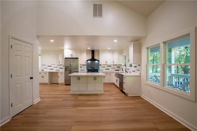 1342 Carter Rd, Decatur, GA 30030 - kitchen featuring stainless steel appliances, wall chimney range hood, tasteful backsplash, white cabinetry, and high vaulted ceiling