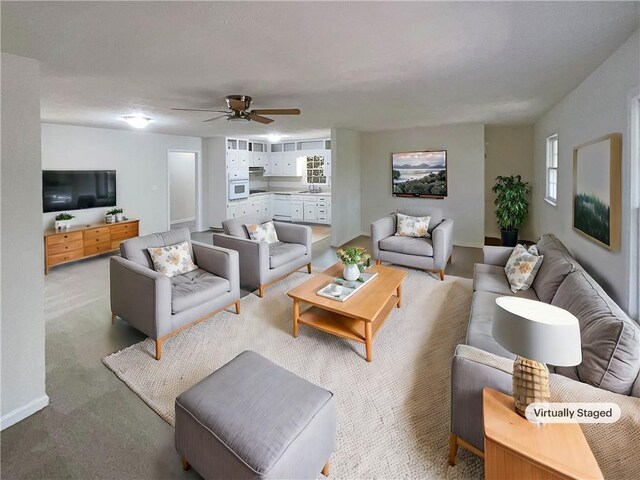 living room featuring sink, light colored carpet, plenty of natural light, and ceiling fan