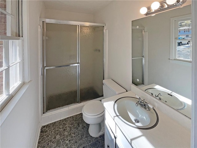 bathroom with an enclosed shower, vanity, toilet, and tile patterned flooring