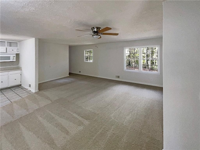 unfurnished living room with ceiling fan, light colored carpet, and a textured ceiling