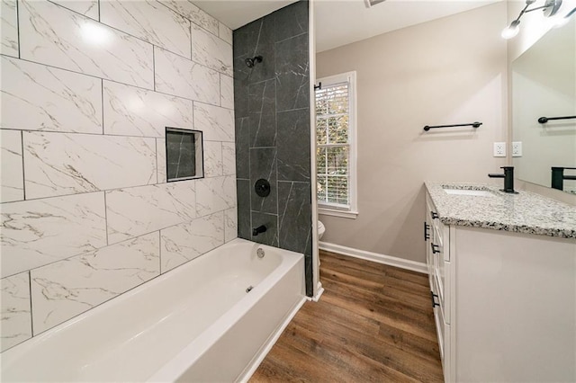 full bathroom with vanity, tiled shower / bath combo, hardwood / wood-style flooring, and toilet