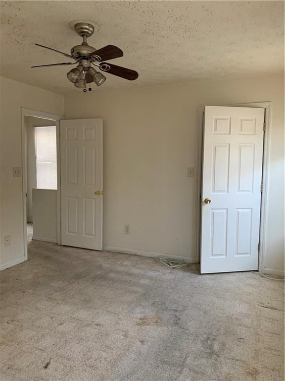 empty room featuring light carpet, a textured ceiling, and ceiling fan