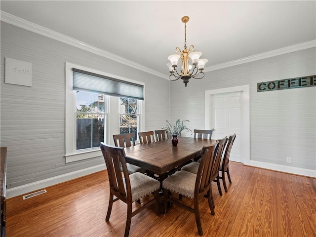 dining room with hardwood / wood-style flooring, an inviting chandelier, and ornamental molding