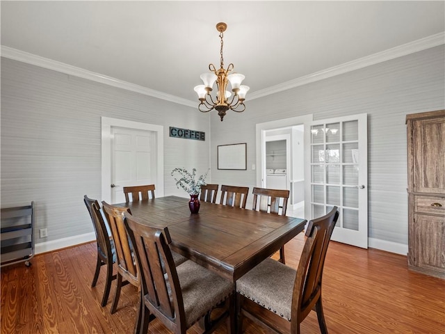 dining area featuring hardwood / wood-style flooring, washing machine and dryer, crown molding, and an inviting chandelier