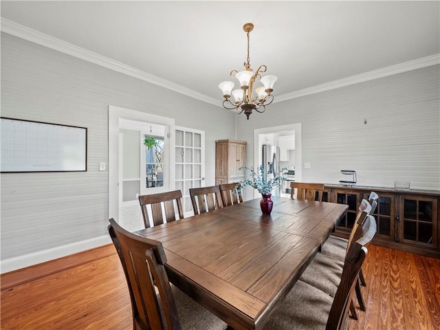 dining room with ornamental molding, wood-type flooring, and an inviting chandelier