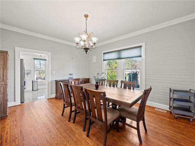 dining space featuring a chandelier, light hardwood / wood-style floors, a wealth of natural light, and ornamental molding