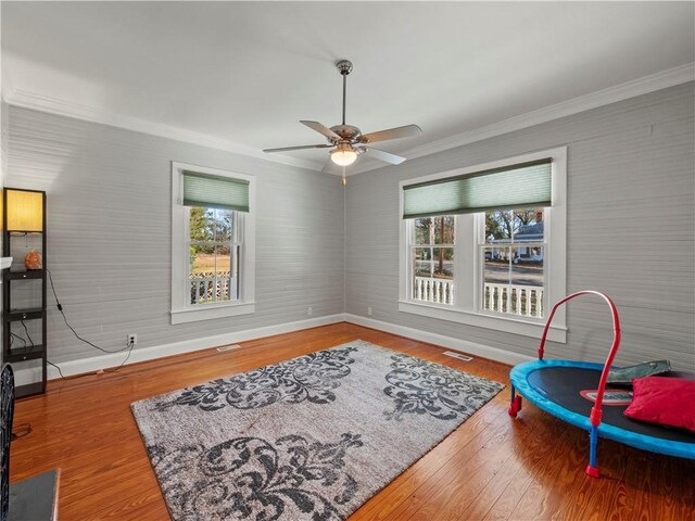 living area with ceiling fan, wood-type flooring, and ornamental molding