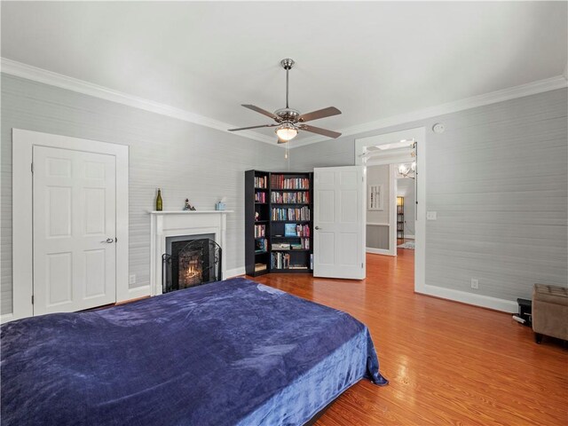 bedroom with wood-type flooring, ceiling fan, and crown molding