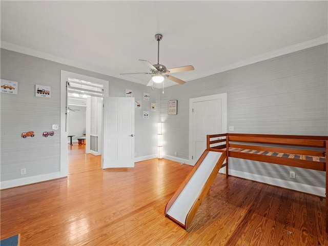 interior space featuring ceiling fan, wood-type flooring, and ornamental molding