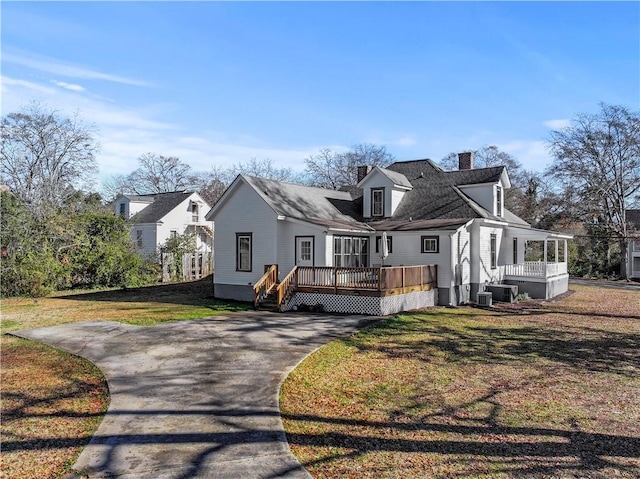 view of front of property featuring central air condition unit, a deck, and a front lawn