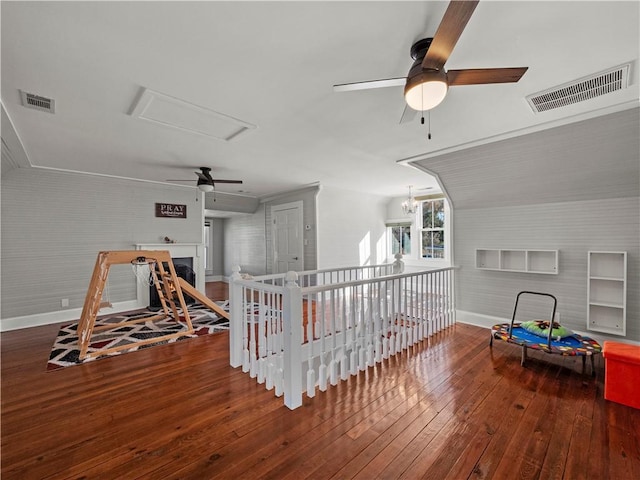 rec room with hardwood / wood-style flooring, ceiling fan with notable chandelier, brick wall, and vaulted ceiling