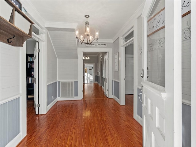 hall featuring a chandelier, wood-type flooring, and crown molding