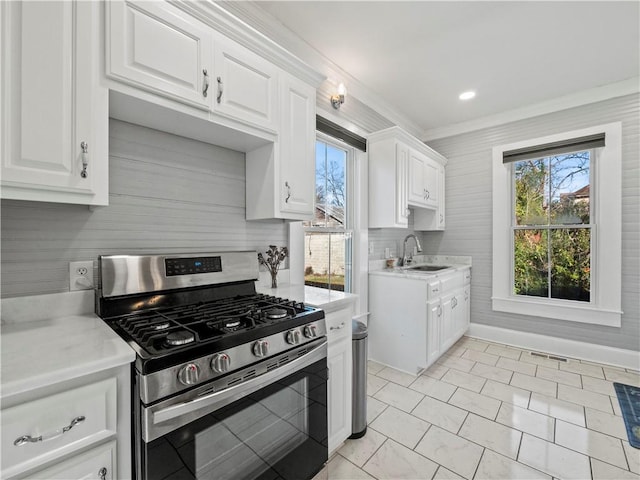 kitchen with white cabinetry, stainless steel range with gas cooktop, crown molding, and sink