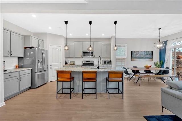 kitchen featuring a sink, a kitchen breakfast bar, appliances with stainless steel finishes, and gray cabinetry