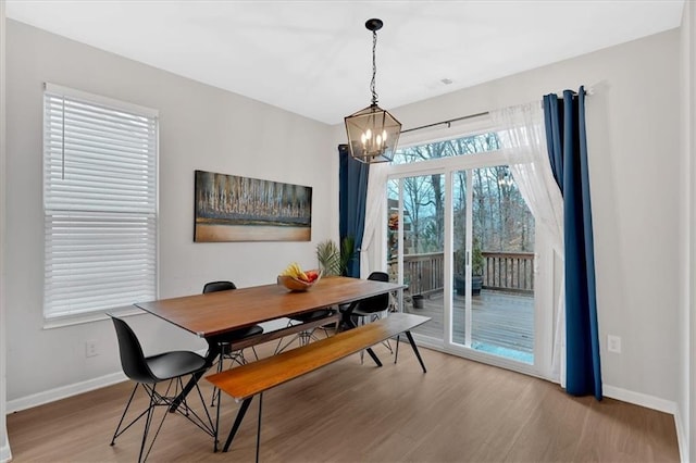 dining space featuring an inviting chandelier, baseboards, and wood finished floors