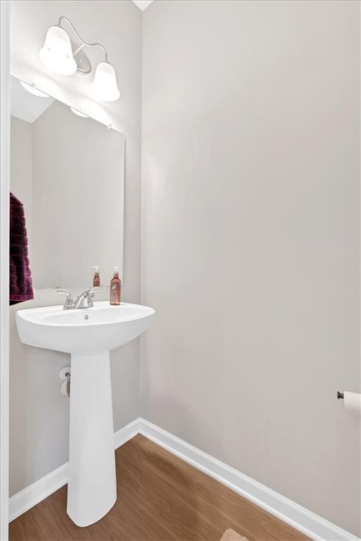 bathroom featuring wood finished floors, baseboards, and a sink