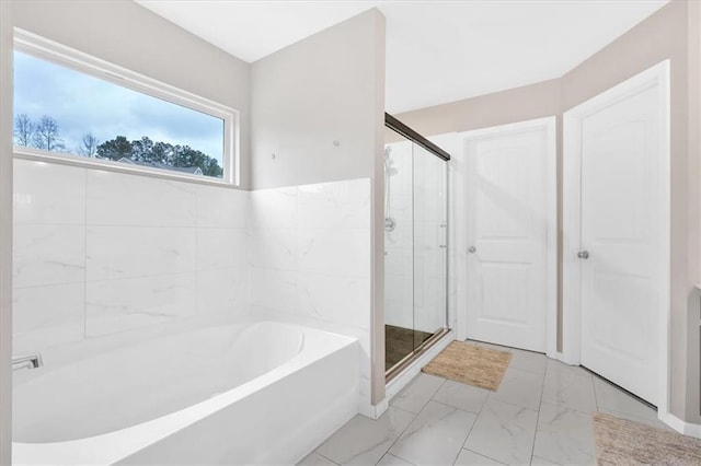 full bathroom featuring a garden tub, marble finish floor, and a stall shower