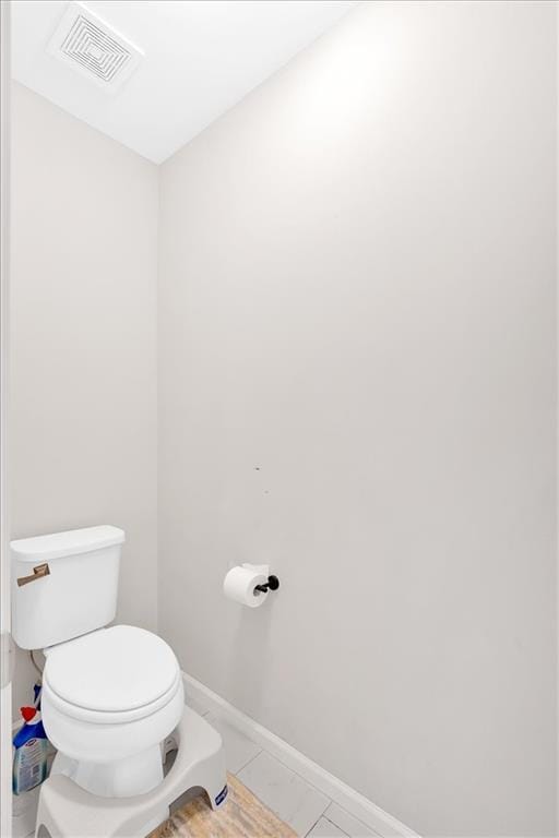 bathroom with tile patterned flooring, toilet, baseboards, and visible vents