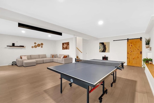 recreation room featuring recessed lighting, light wood-style flooring, baseboards, and a barn door