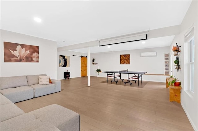 living room with wood finished floors, baseboards, recessed lighting, a wall mounted air conditioner, and a barn door