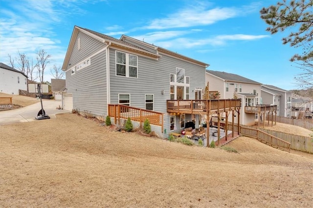 back of house with a deck, fence, a residential view, concrete driveway, and a patio area