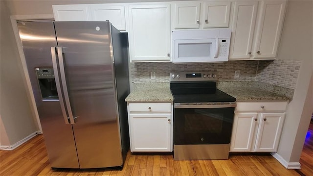 kitchen with white cabinetry, light stone counters, light wood-type flooring, stainless steel appliances, and decorative backsplash