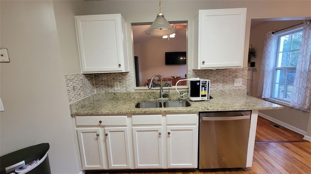 kitchen with decorative light fixtures, dishwasher, sink, and white cabinets