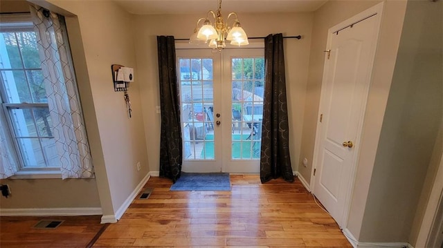 entryway featuring french doors, a chandelier, and light wood-type flooring