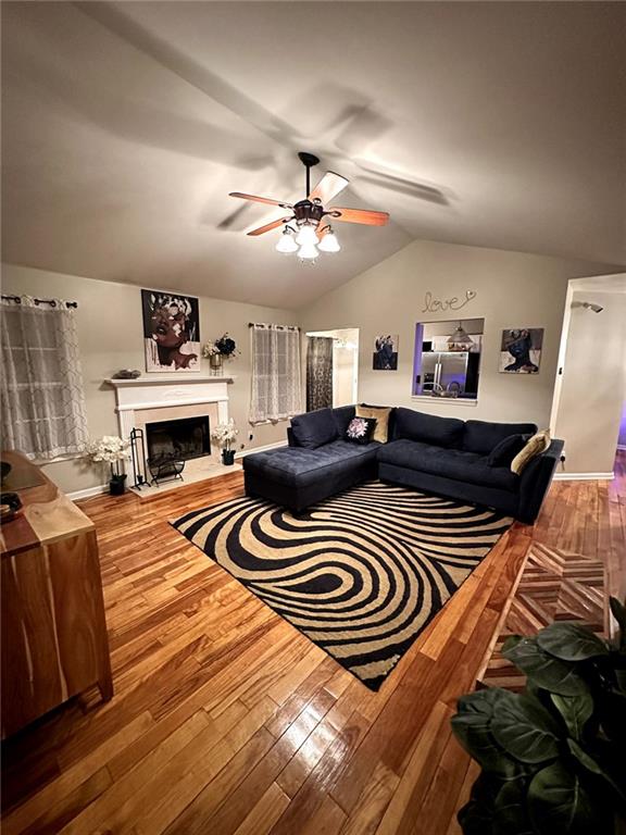 living room featuring hardwood / wood-style floors, vaulted ceiling, and ceiling fan