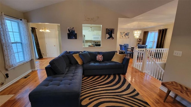 living room featuring hardwood / wood-style flooring, lofted ceiling, and a chandelier