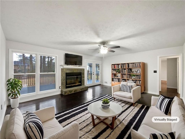 living room featuring a glass covered fireplace, a textured ceiling, a healthy amount of sunlight, and wood finished floors