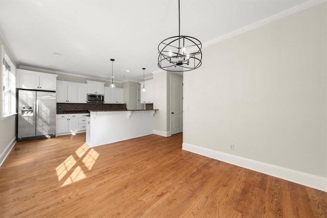 kitchen featuring kitchen peninsula, stainless steel appliances, light hardwood / wood-style flooring, a notable chandelier, and white cabinets