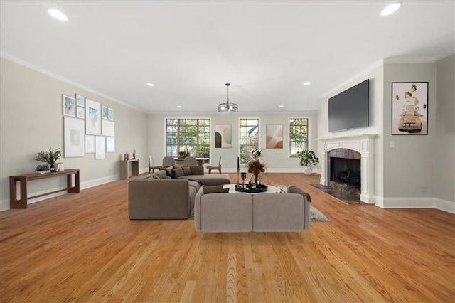 living room with a healthy amount of sunlight, light hardwood / wood-style flooring, crown molding, and a premium fireplace