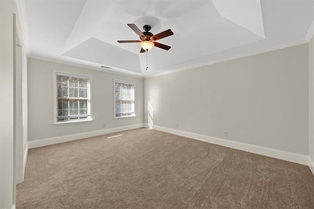 carpeted empty room with a raised ceiling, ceiling fan, and crown molding