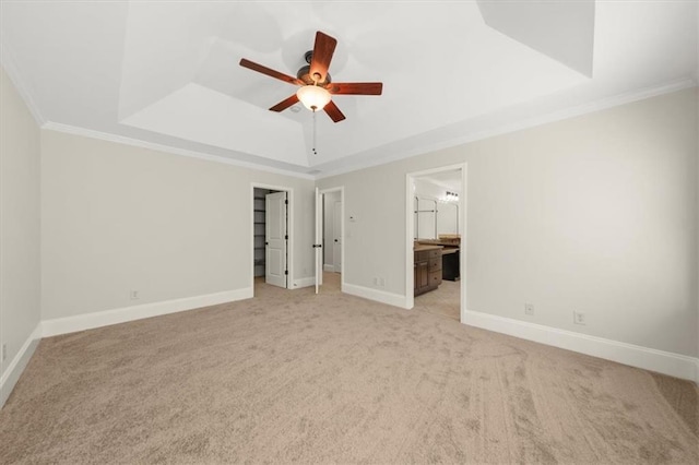 interior space with a tray ceiling, ceiling fan, and ornamental molding